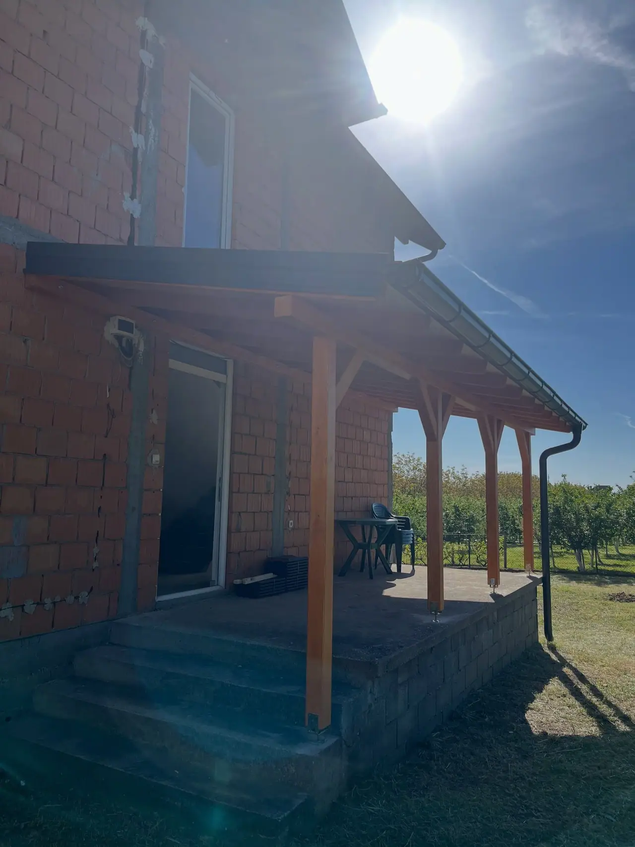 Nadstrešnica sa drvenim stubovima iznad ulaza i stepenica
